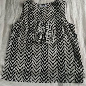 A sleeveless black and beige top with front detailing.